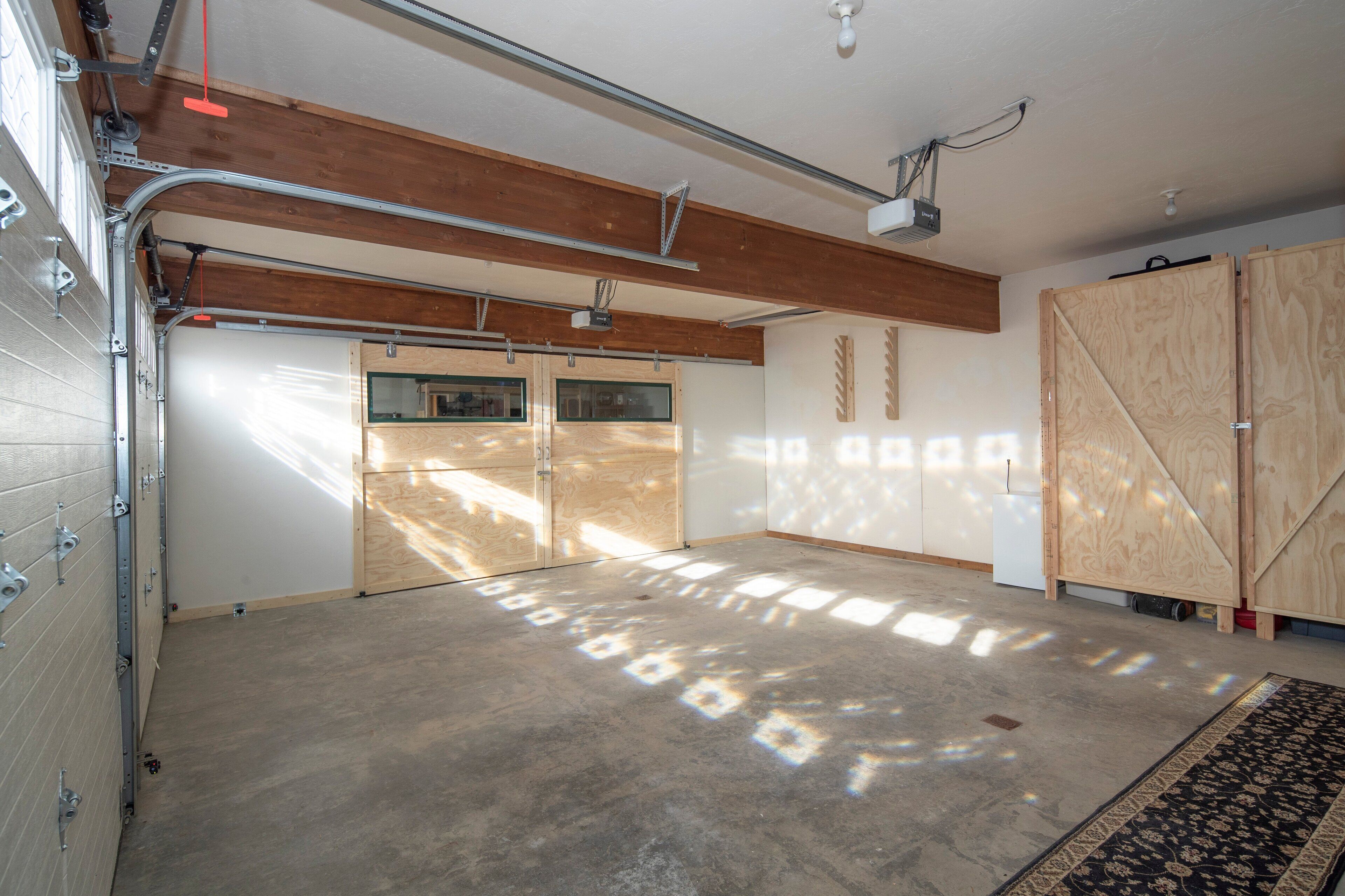 A spacious garage with a concrete floor, wooden walls, and a large door.