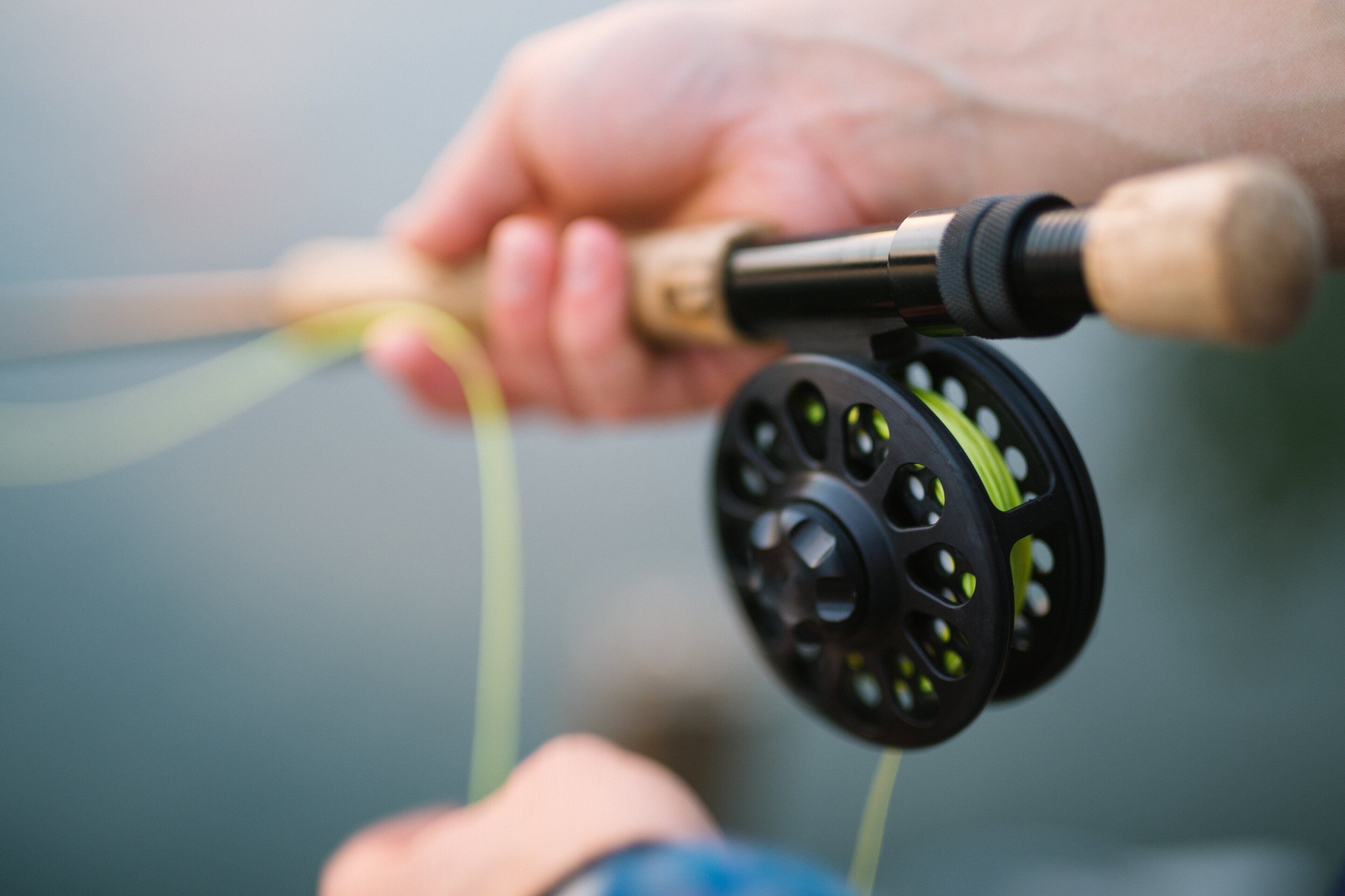 A close-up of a hand holding a fishing reel with a green line.