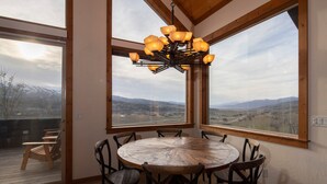 A round wooden table with six chairs in a room with large windows. - Alpine Recharge (Alpine)