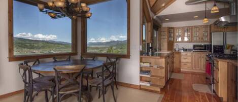 A spacious kitchen with wooden cabinets, a central island, and large windows offering a view of the countryside.