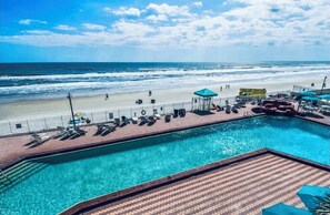 Un espace piscine avec vue sur la plage et l’océan, un belvédère et des chaises longues.
