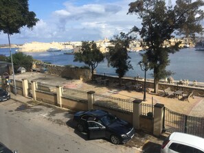 Um calçadão à beira-mar com bancos e um carro estacionado.