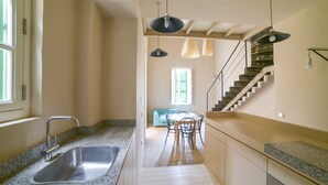 A kitchen with a granite countertop, stainless steel sink, and a staircase leading to a dining area. - AF - Casa Rooms (Valletta)