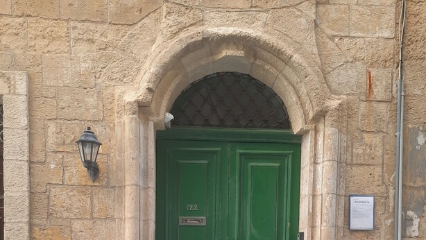 A green double door with a number plate, set in a stone building with a small archway above it. - AF - Casa Rooms (Valletta)