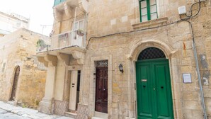 A stone building with a green door and a balcony with railings. - AF - Casa Rooms (Valletta)