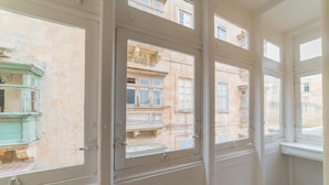 A room with multiple windows, each with a view of old buildings. - AF - Casa Rooms (Valletta)