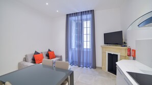 Una sala de estar moderna con sofá, mesa de comedor, televisor de pantalla plana y chimenea.