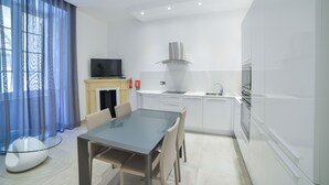 Una cocina moderna con armarios blancos, una mesa de comedor de vidrio y una estufa empotrada.