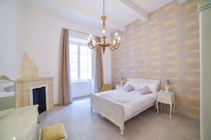 Un dormitorio con cama, mesita de noche, lámpara y espejo.