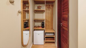 A compact room with a built-in mini-fridge, a coffee maker, and a small shelf with a decorative fish. - Vila Sal Noronha (Fernando de Noronha)