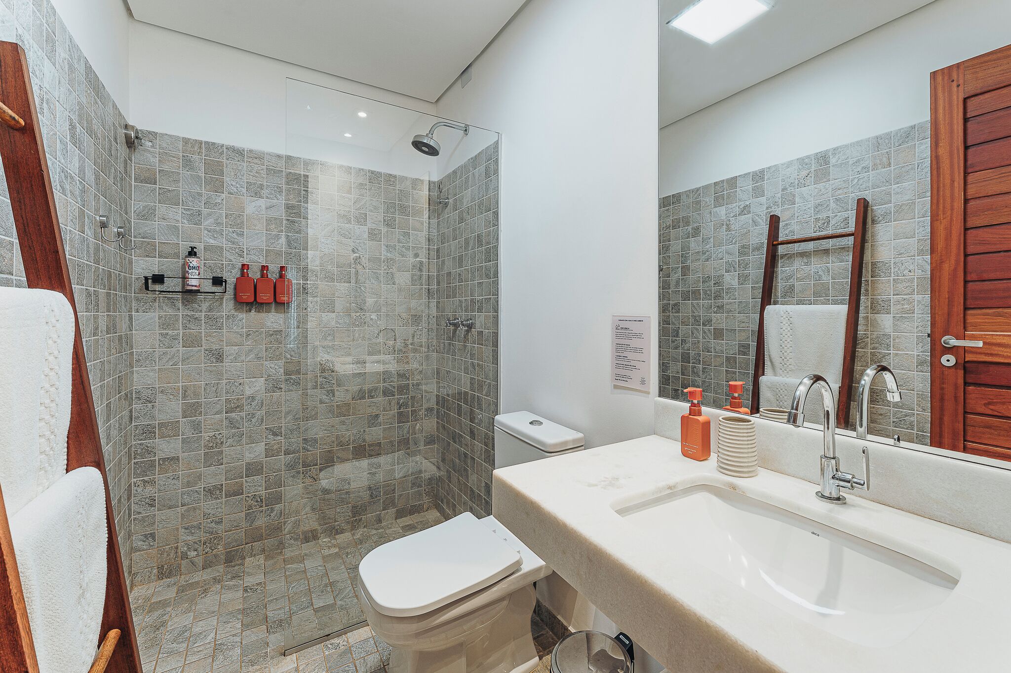 A bathroom with a shower, toilet, sink, and a mirror.