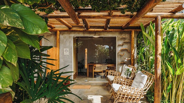 A covered outdoor seating area with wicker furniture and lush greenery. - Vila Sal Noronha (Fernando de Noronha)