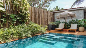 A swimming pool with steps leading into it, surrounded by lush greenery and a wooden deck. - Vila Sal Noronha (Fernando de Noronha)