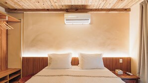 A hotel room with a wooden ceiling, a bed with white bedding, a nightstand, and a wooden wardrobe. - Vila Sal Noronha (Fernando de Noronha)