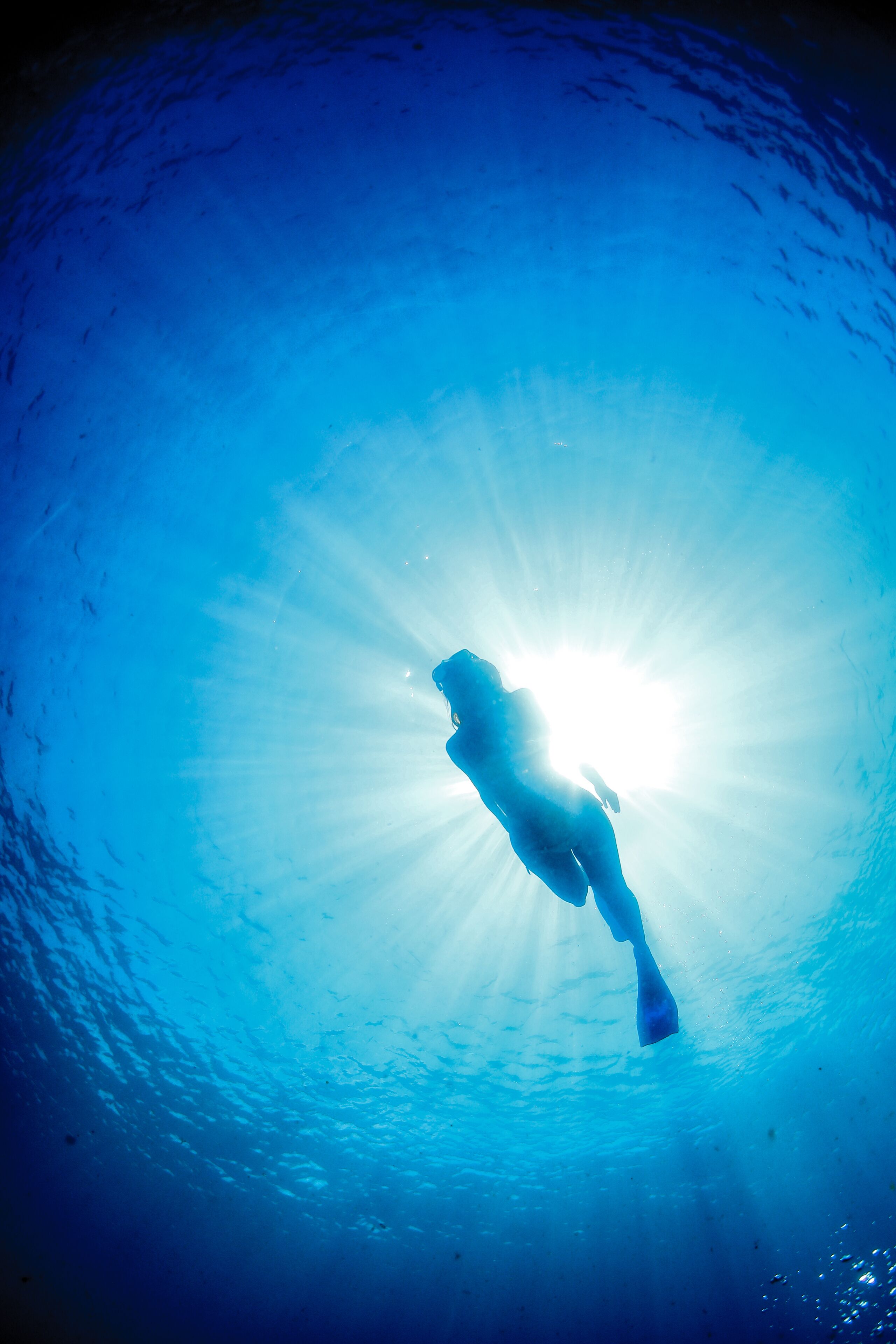 A person swimming in a clear blue water body.