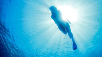 A person swimming in a clear blue water body.