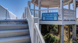 A wooden staircase leading to a covered area with a sign reading "Kure-by-the-Sea Gazebo PRIVATE". - Ocean Retreat with Private Beach Access (Kure Beach)