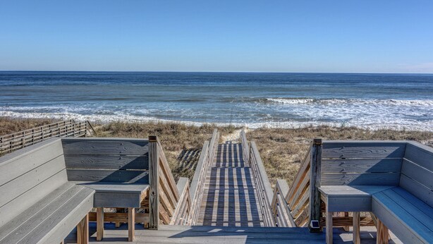 A wooden boardwalk leading to the beach with benches and a railing. - Ocean Retreat with Private Beach Access (Kure Beach)