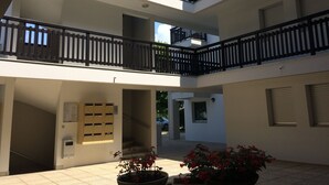 A multi-level building with balconies, a staircase, and potted plants.