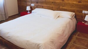 Siististi pedattu sänky valkoisilla lakanoiden kanssa huoneessa, jonka seinät on verhoiltu puupaneeleilla ja jossa on punaiset yöpöydät, joissa on lamput.