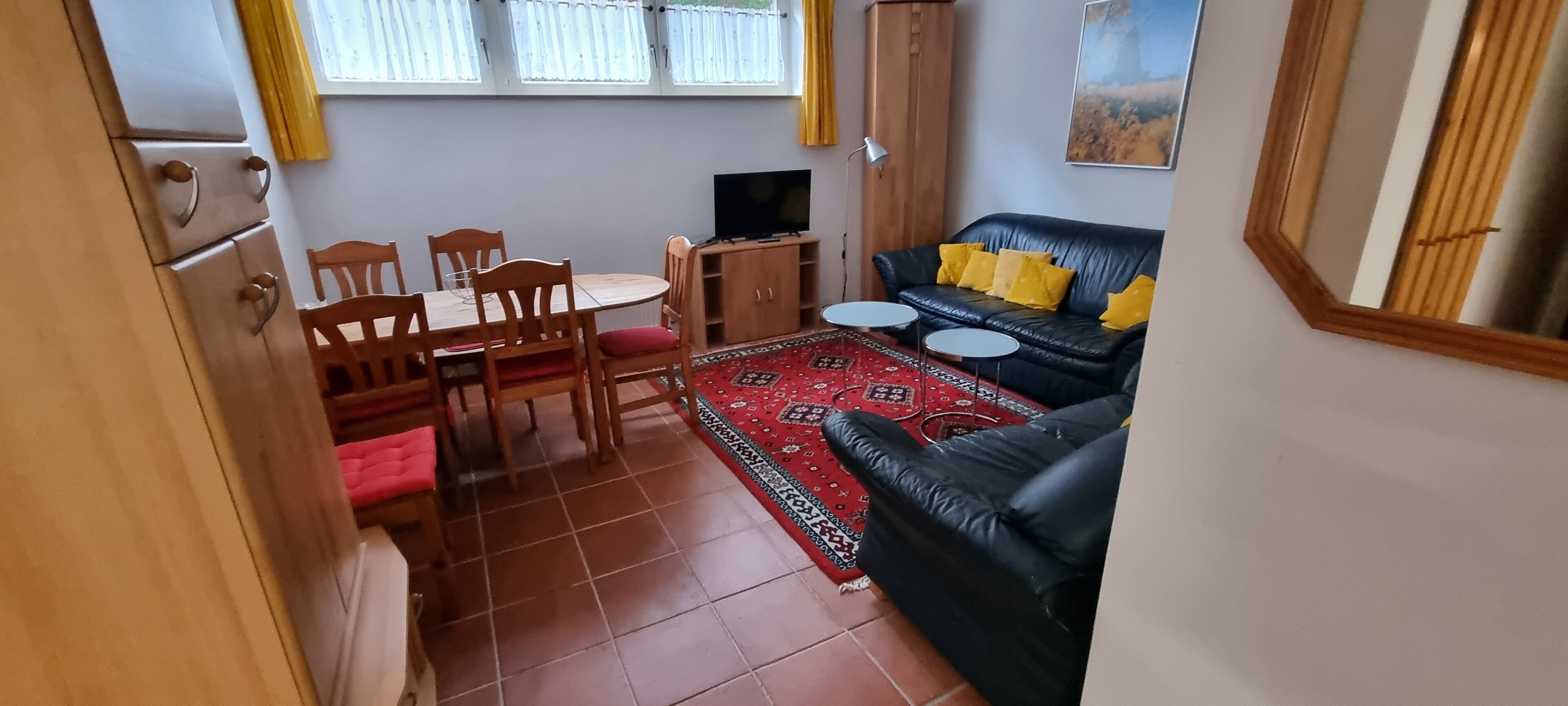 A compact living space with a dining area, a sofa, and a television.