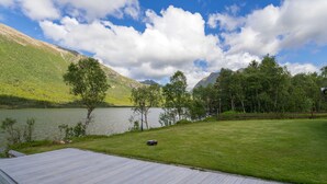 A wooden deck overlooking a lake with mountains in the background. - VESTERALEN LODGE - TOP QUALITY IN THE VESTERALEN and LOFOTEN (Sortland)