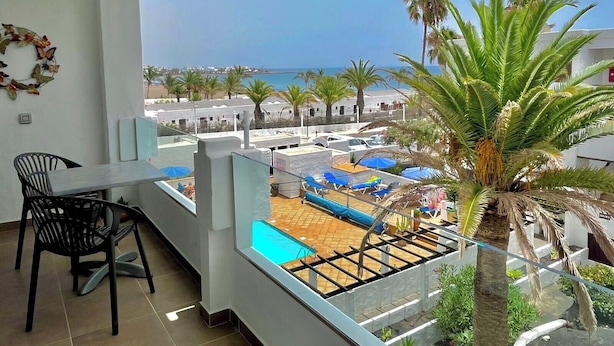 Ein Balkon mit Blick auf Poolanlage und Meer.