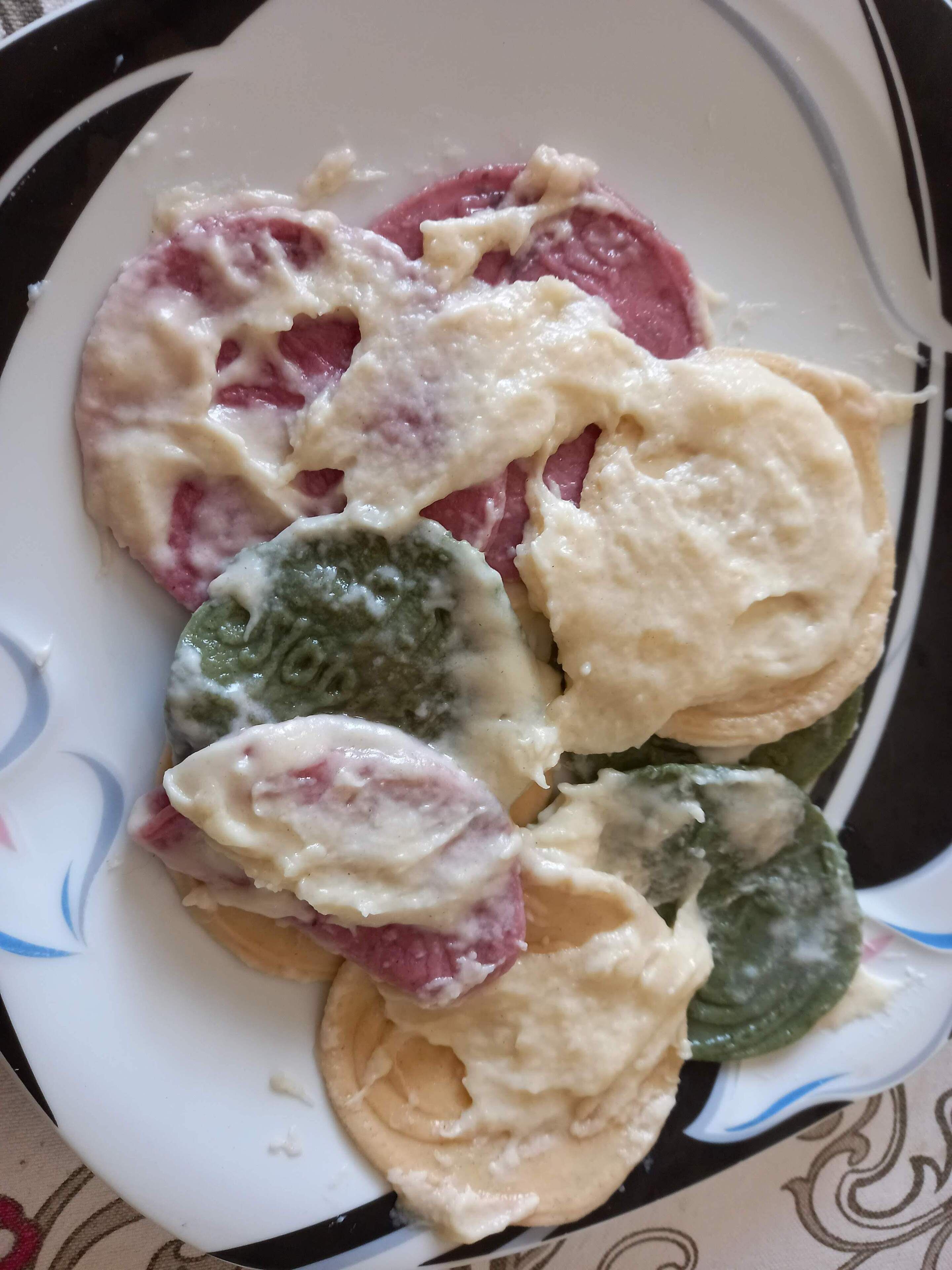 Une assiette contenant divers aliments, notamment des tranches de viande et des légumes verts nappés d’une sauce crémeuse.