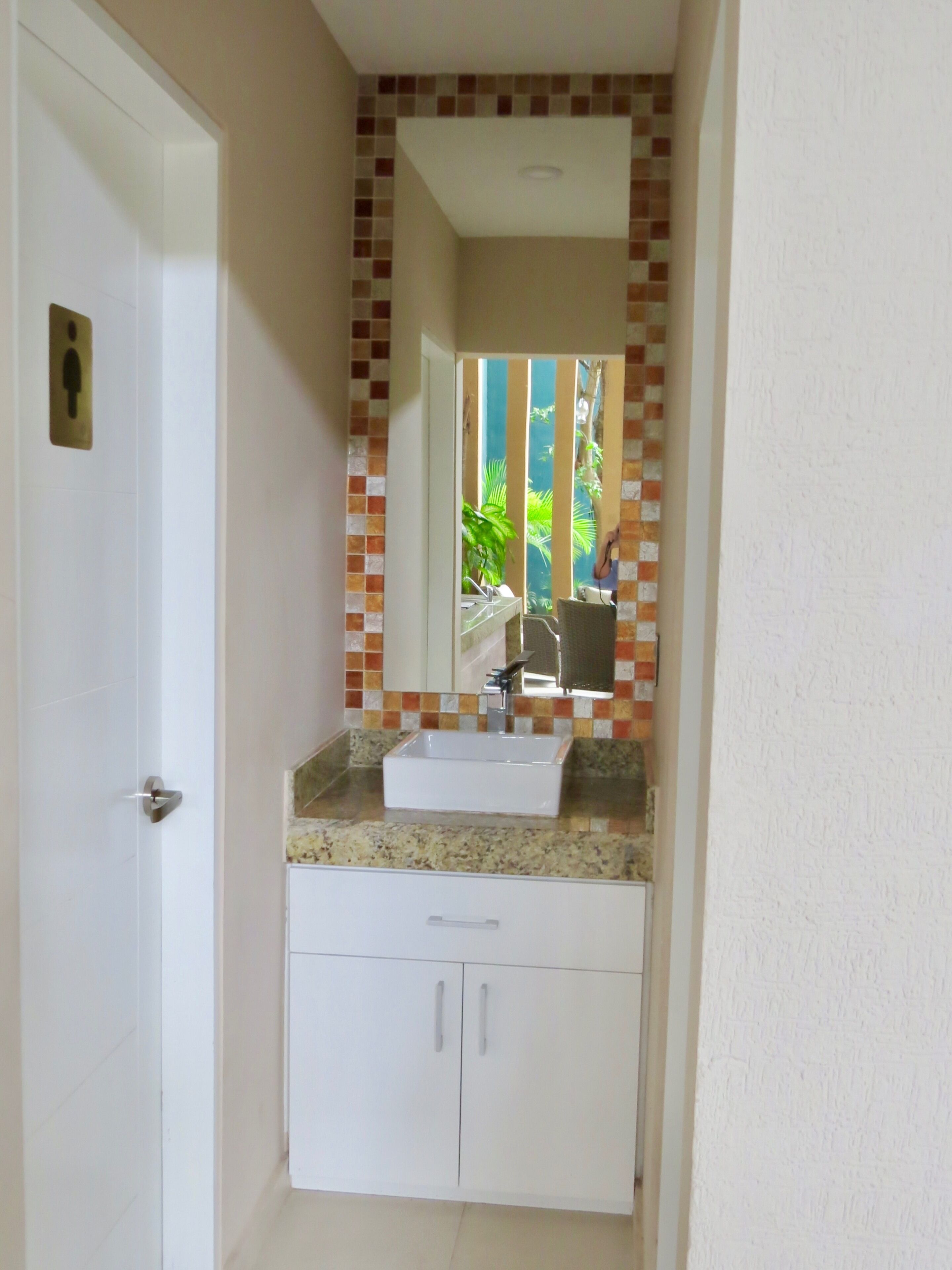 A bathroom with a white sink, a mirror, and a tiled backsplash.