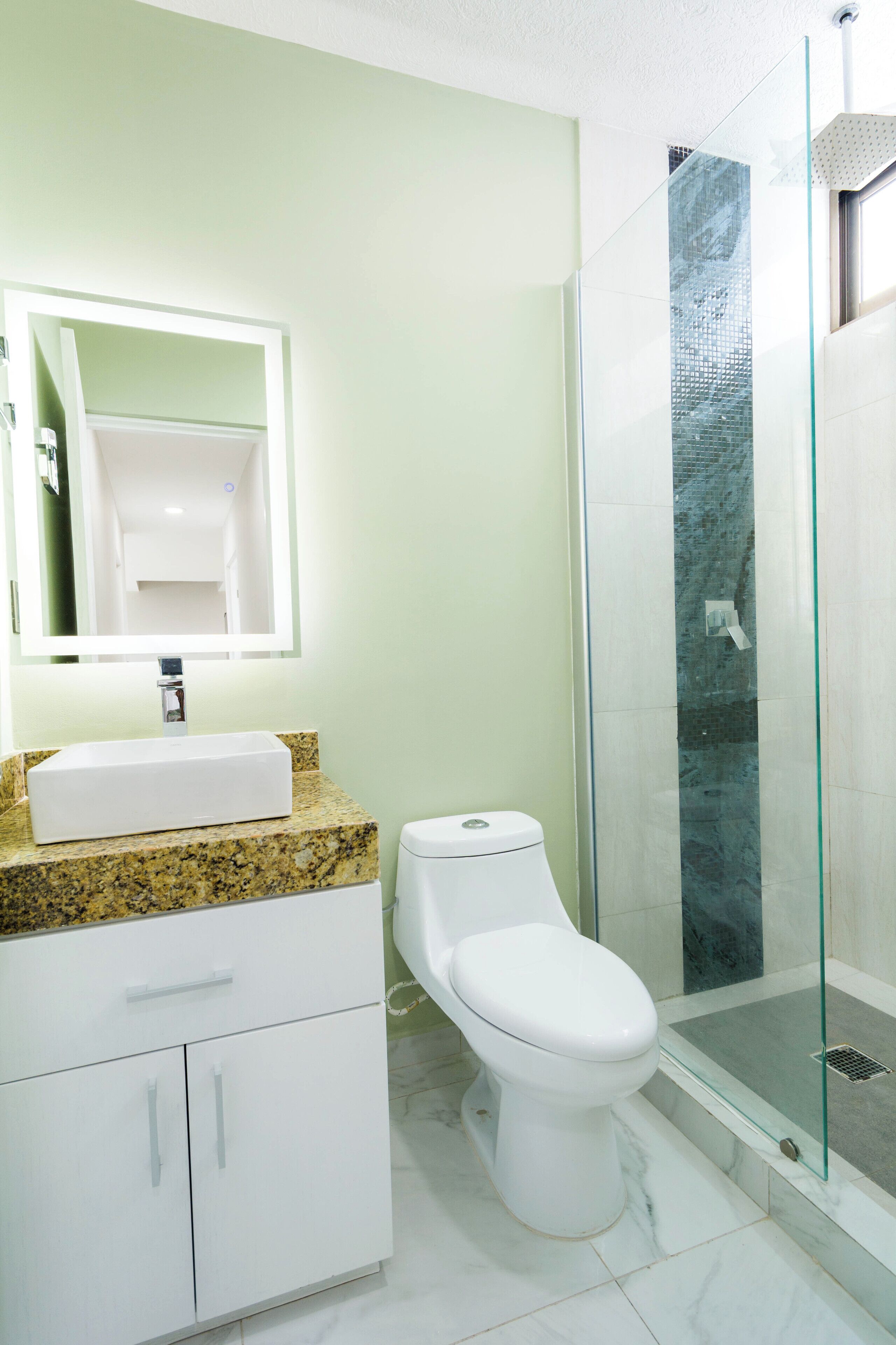 A bathroom with a white sink, a toilet, and a glass-enclosed shower.