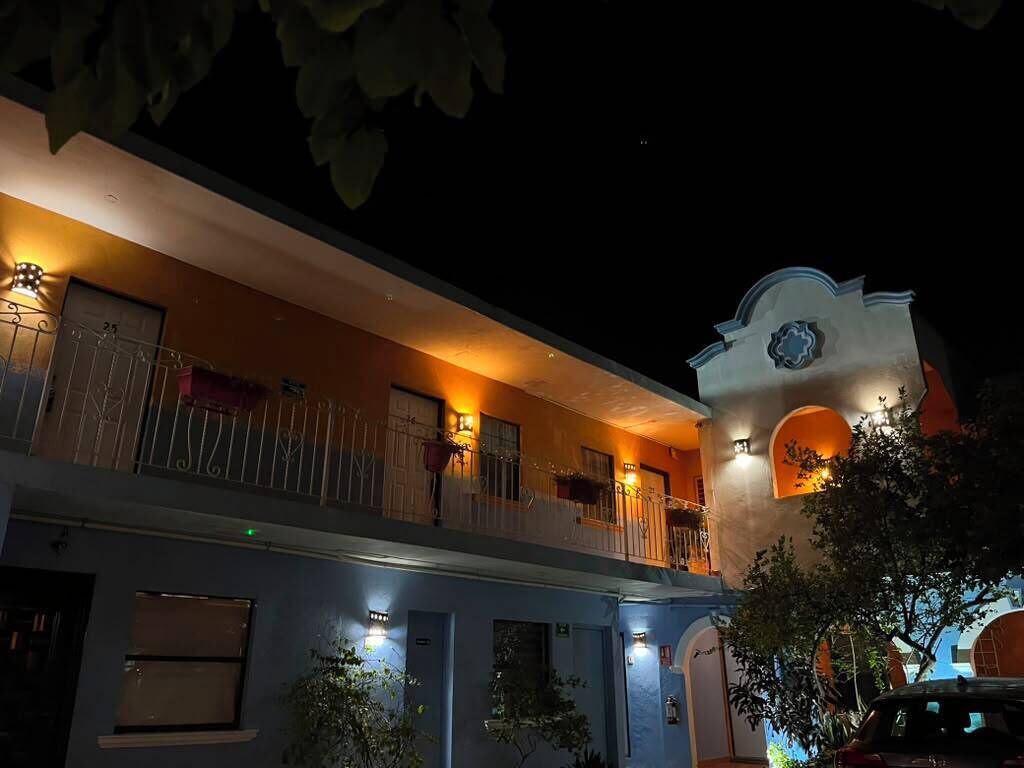 A two-story building with balconies, a bell tower, and outdoor lighting.