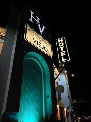 Une enseigne d’hôtel avec les lettres « HV » et le mot « Hotel », indiquant qu’il s’agit d’un établissement hôtelier.