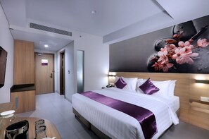 Una habitación de hotel con una cama, mesita de noche y un cuadro grande con motivos florales en la pared.