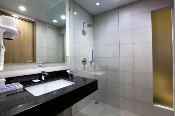 A modern bathroom with a black countertop, white sink, and a glass-enclosed shower.