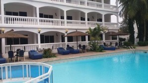Un hotel con zona de piscina, varios balcones y mobiliario de exterior.