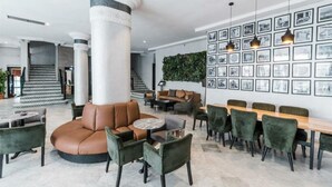 A modern lobby with a central seating area, a staircase, and a wall adorned with framed pictures. - Casablanca Hotel (Casablanca)