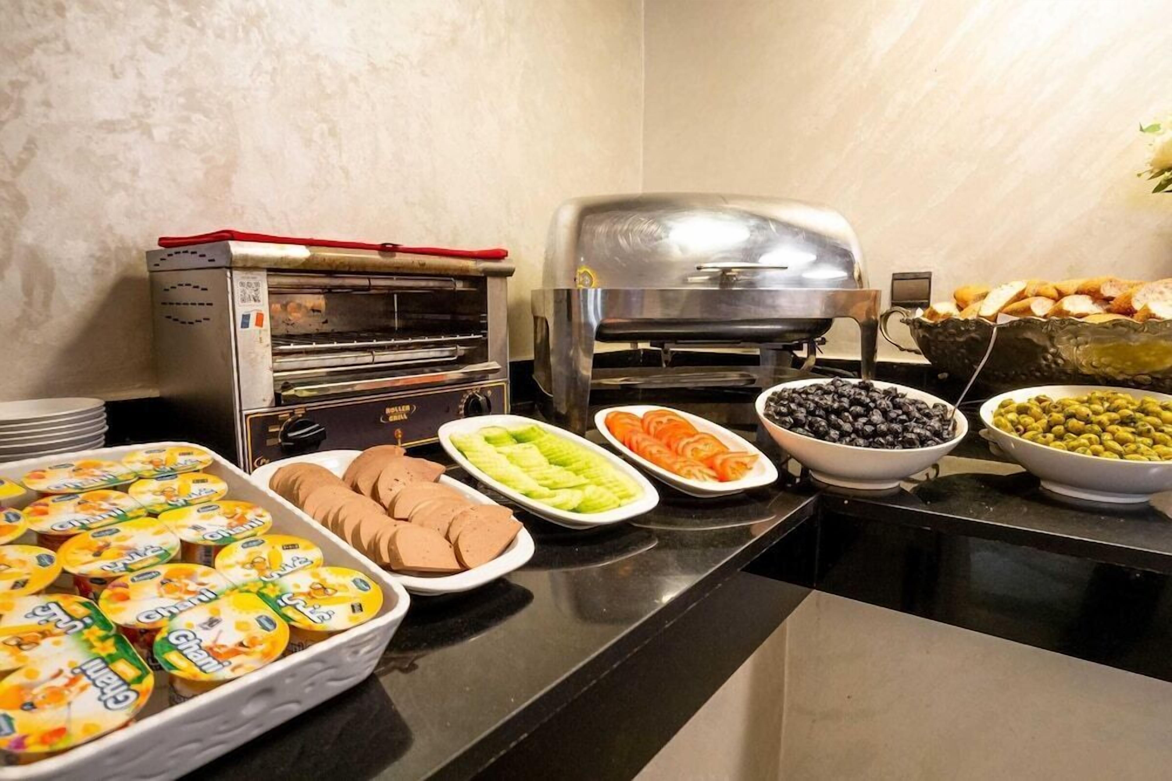 Un bufé con diversos alimentos, incluyendo yogur, verduras en rodajas y aceitunas.
