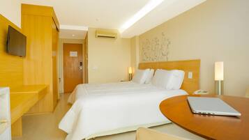 A hotel room with a bed, bedside table, desk, and a laptop.