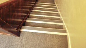 Una escalera con barandillas de madera y peldaños alfombrados.