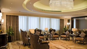 Un lobby de hotel lujoso con muebles ornamentados, una gran araña y una alfombra estampada.
