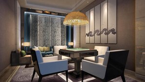 Un moderno salón con una mesa redonda, dos sillones, una lámpara colgante decorativa y una pared estampada.