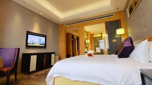 Habitación de hotel con una cama grande, un televisor en la pared y un espejo que refleja el cuarto.