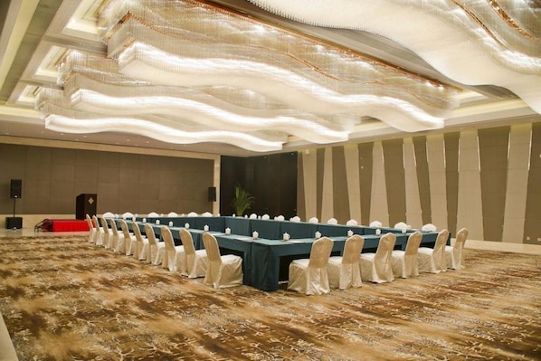 A conference room with a long table, white chairs, and a patterned carpet. - Firth Jinling Grand Hotel (Zhenjiang)