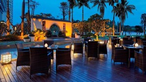 An outdoor dining area with wicker furniture and a small building with an archway. - Wanda Realm Guangzhou Zengcheng (Guangzhou)