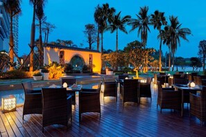 An outdoor dining area with wicker furniture and a small building with an archway. - Wanda Realm Guangzhou Zengcheng (Guangzhou)