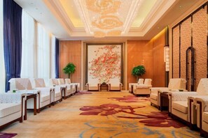 A hotel lobby with a long reception desk, multiple seating areas, and a large floral painting on the wall. - Wanda Realm Guangzhou Zengcheng (Guangzhou)