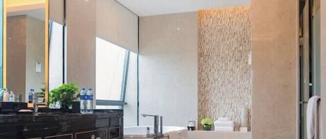 A modern bathroom with a large mirror, a bathtub, and a vanity with a dark countertop.