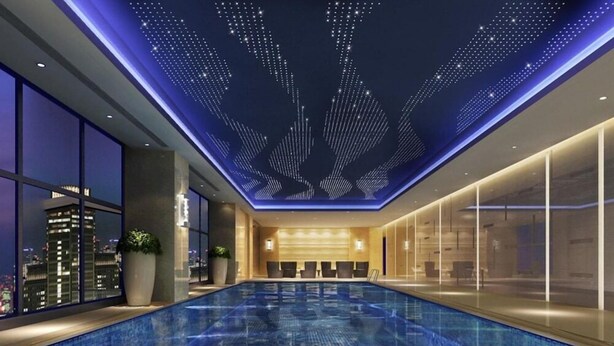 A modern indoor swimming pool with a city view, a ceiling with a star-like pattern, and a reception area with seating. - Wanda Realm Guangzhou Zengcheng (Guangzhou)