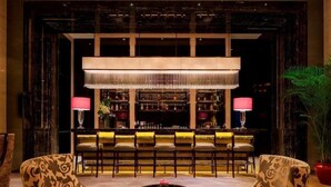 A bar area with a long counter, multiple chairs, and a large chandelier. - Wanda Realm Guangzhou Zengcheng (Guangzhou)