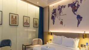 Ett hotellrum med en säng, två stolar, ett skrivbord, en karta på väggen och en världskarta.